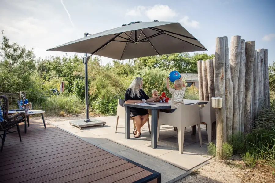 Familie op het terras van chalet op Camping & Beachresort Julianahoeve in Zeeland